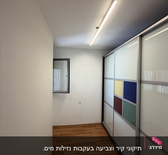 מסדרון עם רצפת עץ ודלתות הזזה צבעוניות